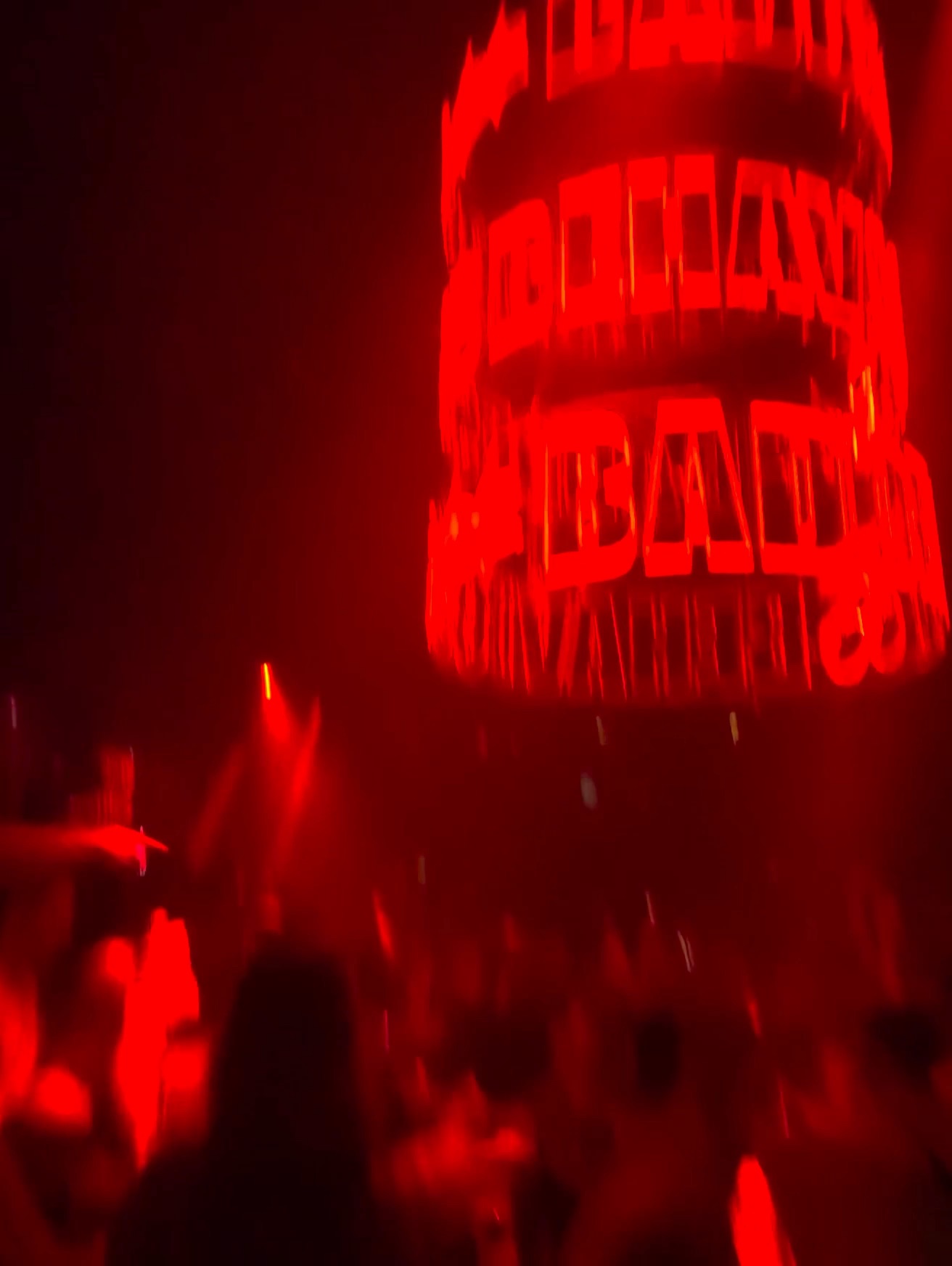 A red-lit nightclub crowd beneath an illuminated cylindrical sign in Ibiza