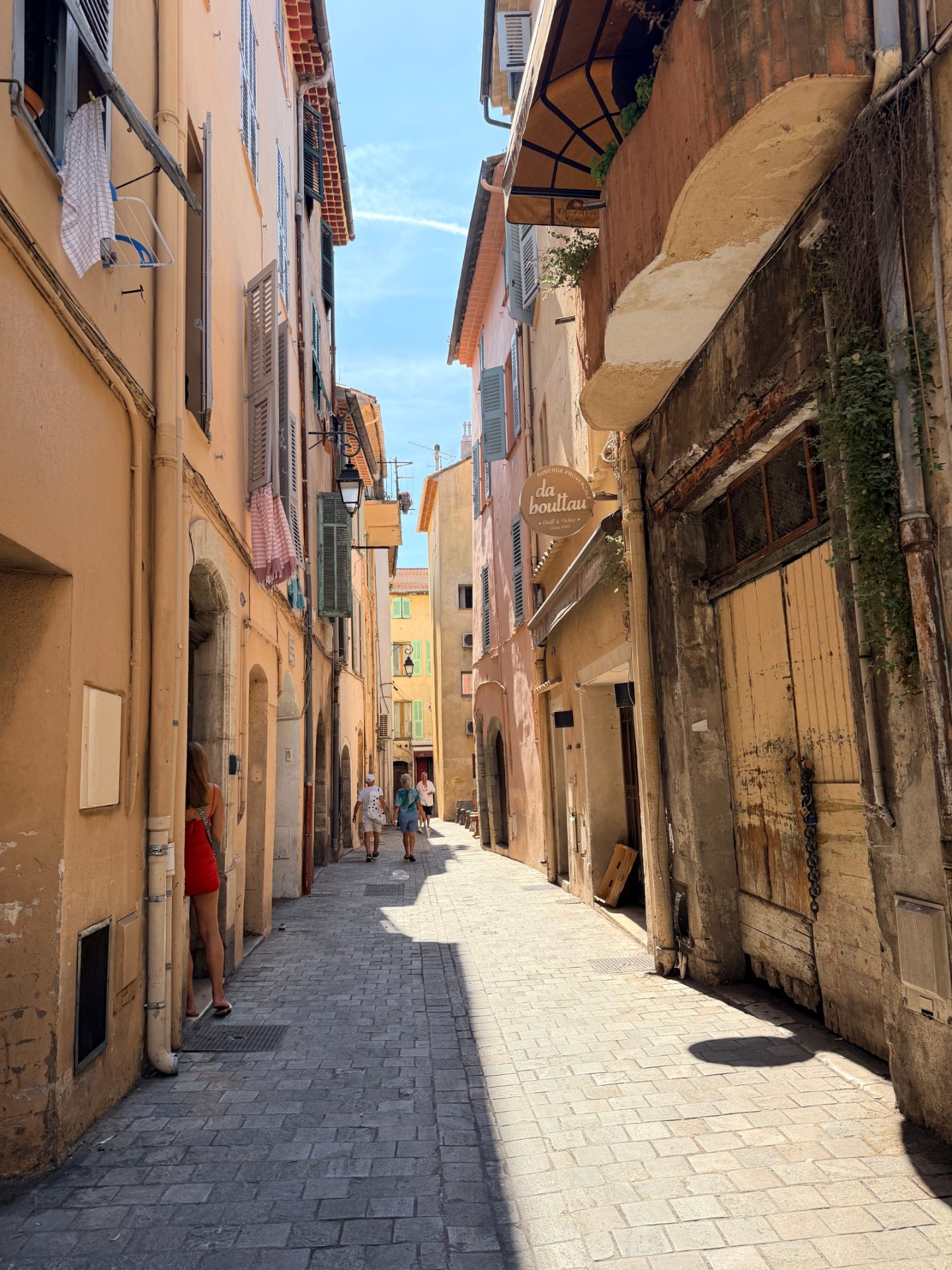 A narrow cobblestone alley between pastel buildings in the old town of Cannes