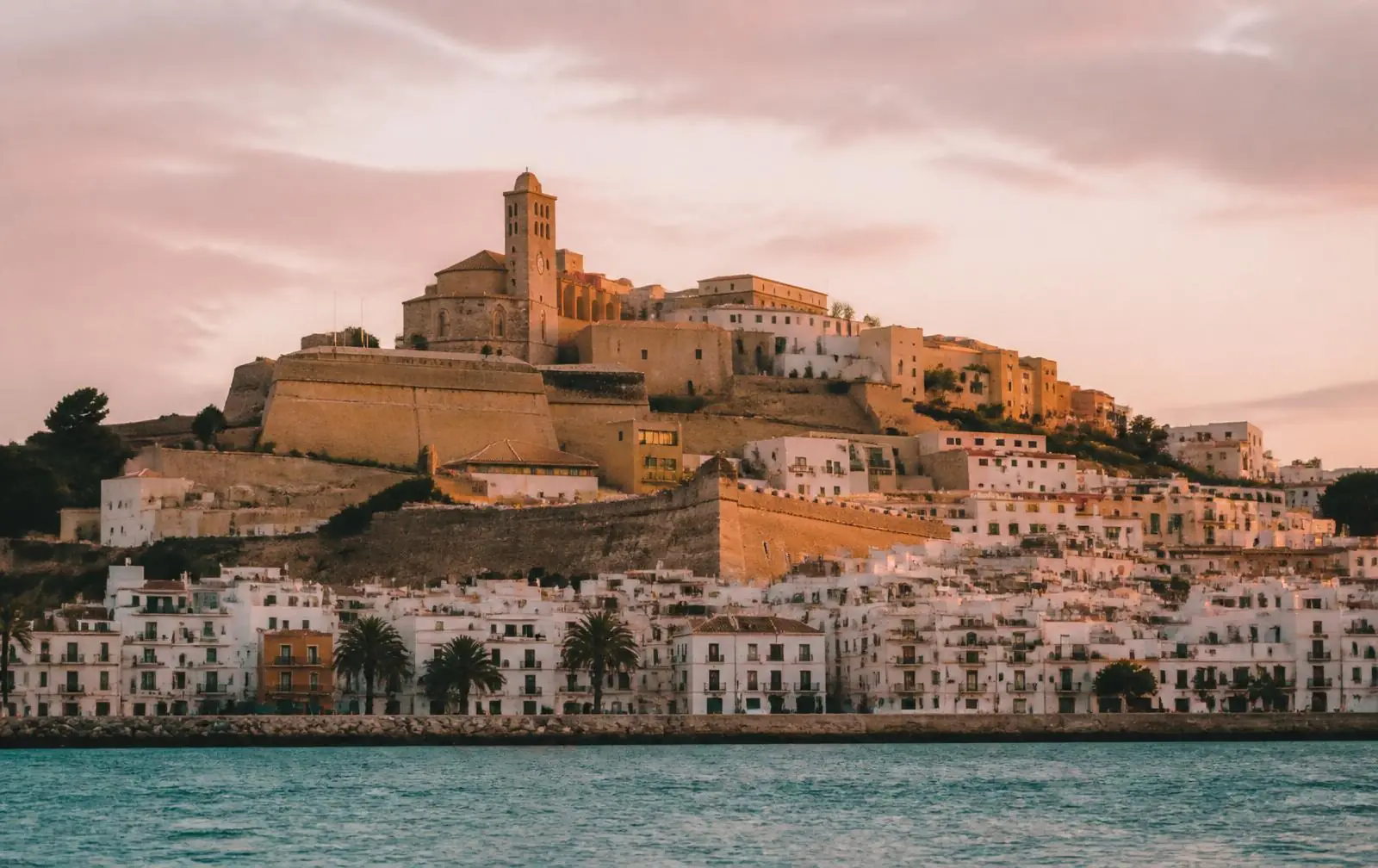 Dalt Vila old town of Ibiza rising above whitewashed harbor houses at golden hour, Balearic port on the 2026 Mediterranean Solar Eclipse Cruise
